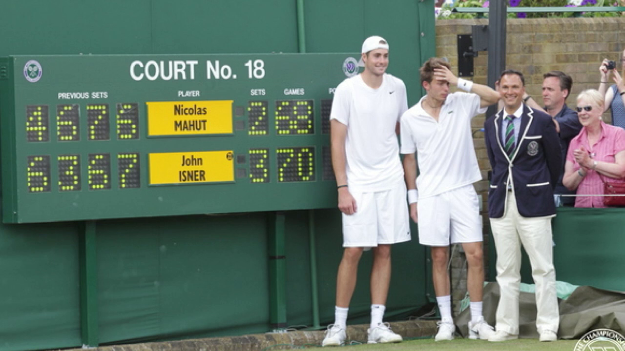 Photo of two tennis players standing in front of a scoreboard reading 70-68