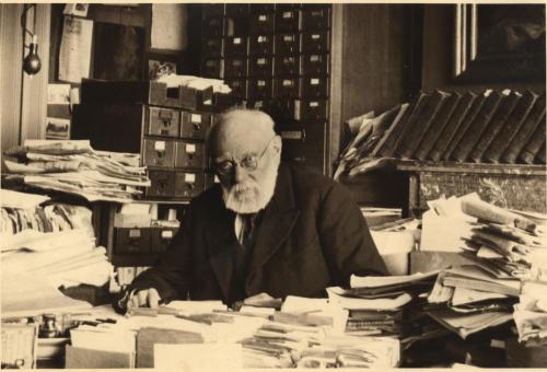 Photo of Paul Otlet sitting at a desk among his papers