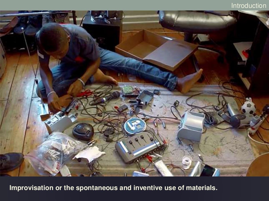 A young man sitting on the floor surrounded by dismantled electronics