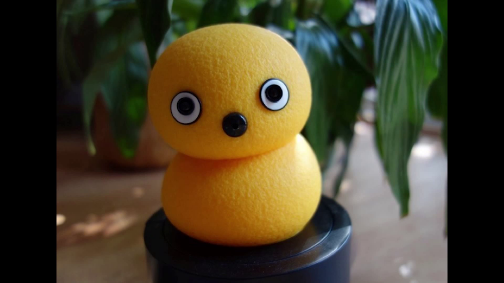 A small robot, roughly resembling two yellow foam balls stacked atop each other, with eyes and a nose.