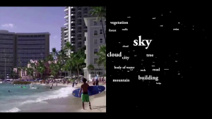 Still from a movie showing a young man carrying a surfboard down a beach in front of several buildings, with a word cloud at right identifying several visible features.