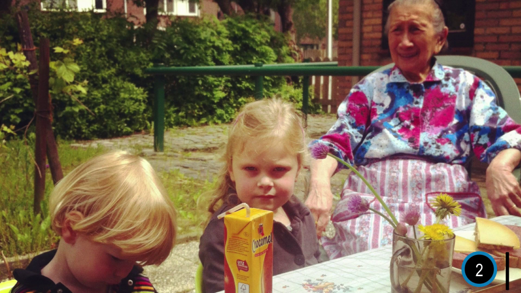 And older woman and two children seated at a backyard table