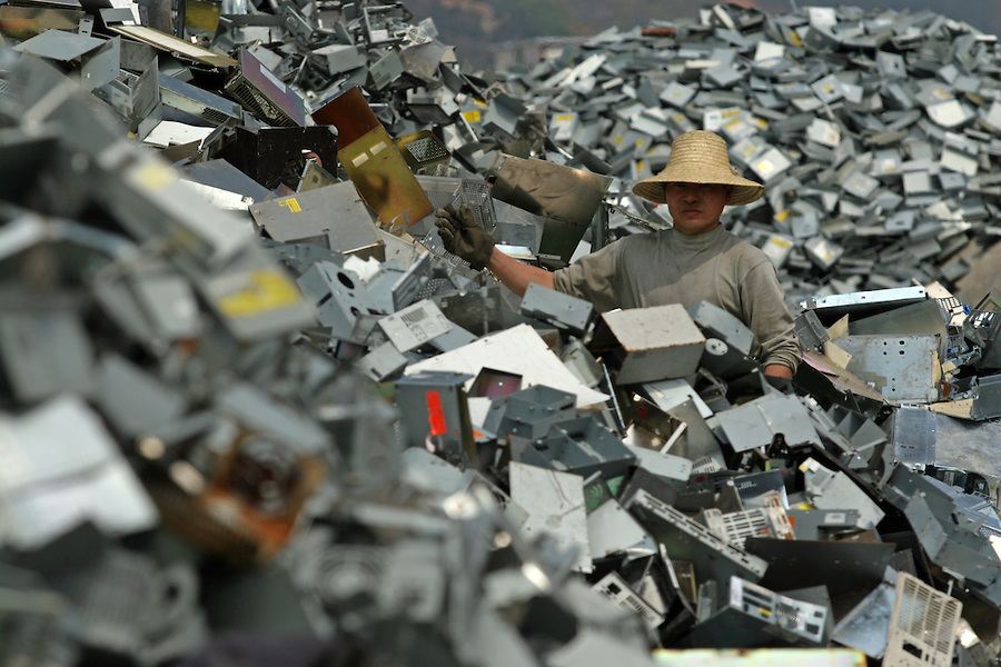 A junk yard worker sorts e-waste worker makes plastic flowers out of recycled plastics in Nanyang, China.