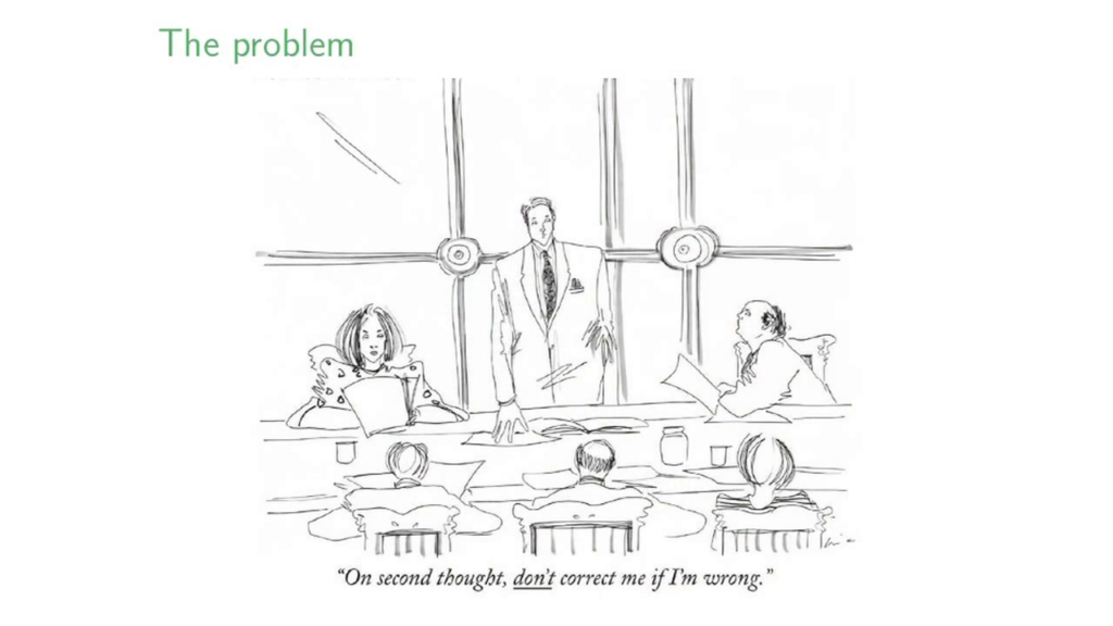 A man standing before several people at a meeting table, staying, "On second thought, DON'T correct me if I'm wrong."