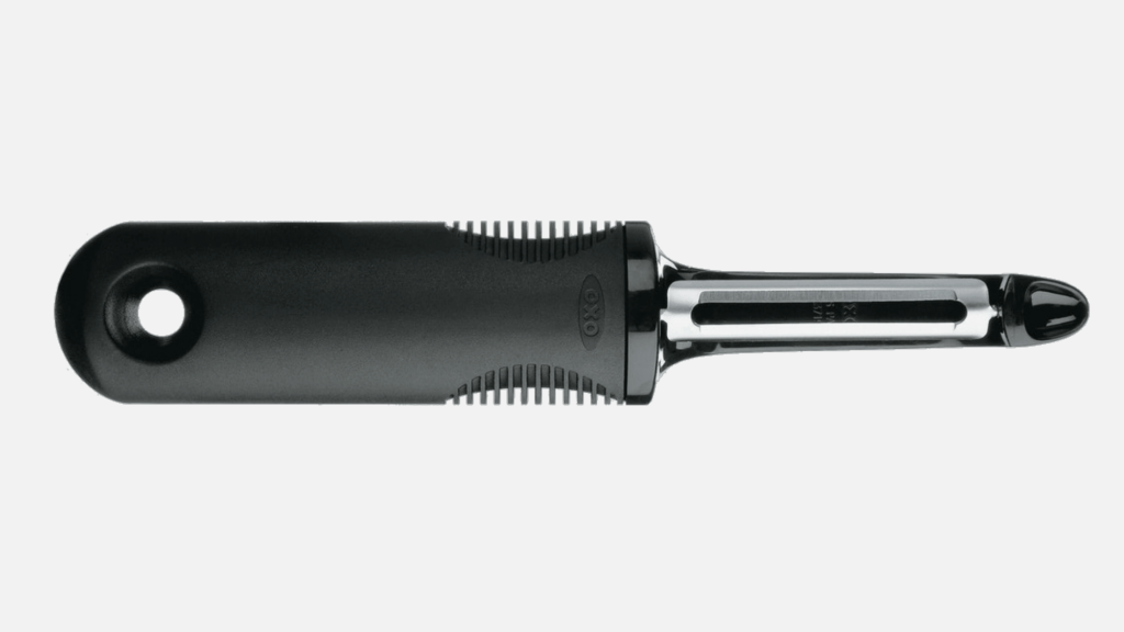 An OXO vegetable peeler, having a somewhat oversized cushioned black handle for ease of use.