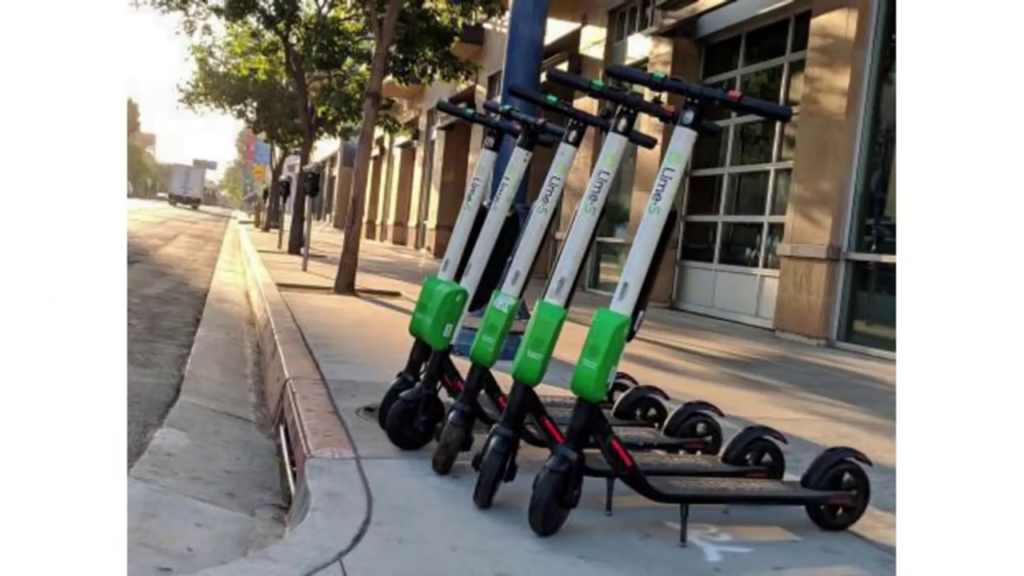 A row of electric scooters parked on a sidewalk.